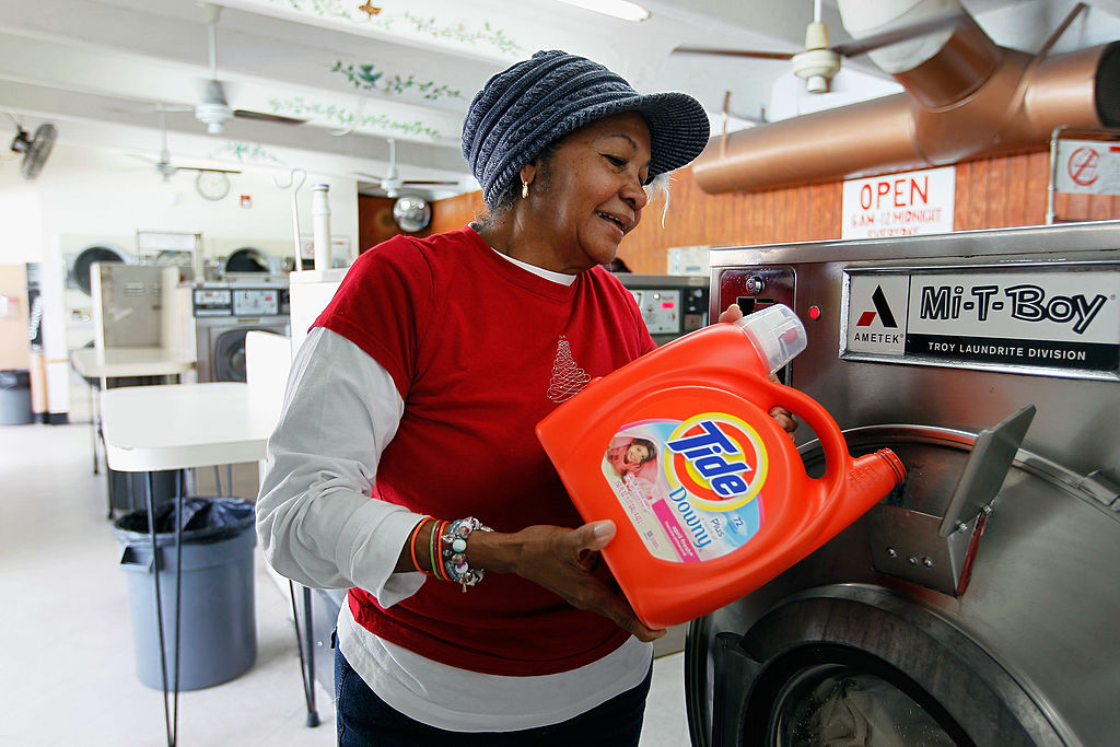 woman putting detergent into washing machine