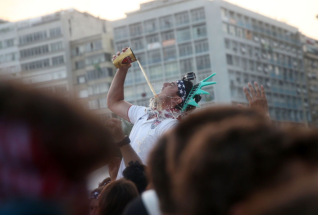 Man chugging beer with statue of liberty head piece on