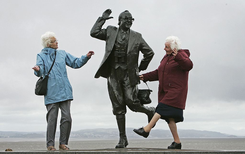 happy elderly women next to statue