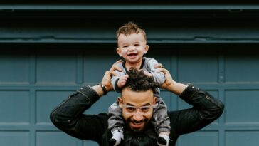 man in black leather jacket carrying boy in black leather jacket