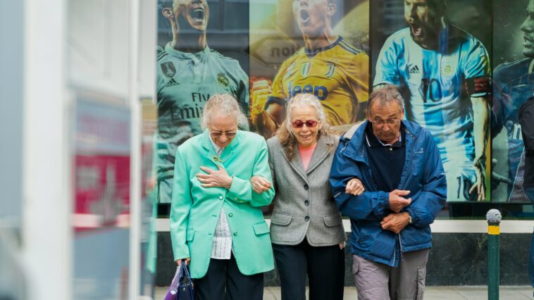 two women and man walking in the street during daytime