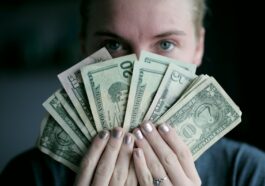 person holding fan of U.S. dollars banknote